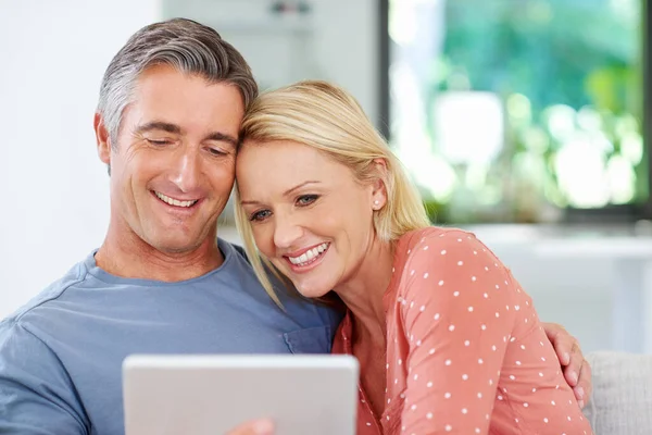Relaxing together with some online entertainment. Shot of a mature couple relaxing with their digital tablet at home. — Stock Photo, Image