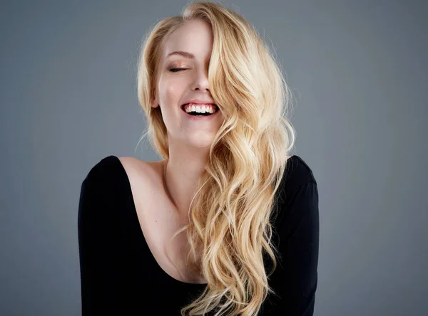 Peu importe la bonne journée des cheveux, passez une super journée des cheveux. Portrait studio d'une jolie jeune femme avec de beaux cheveux blonds longs riant sur un fond gris. — Photo