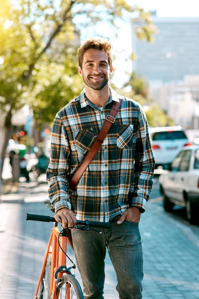 All I need are two wheels. Shot of a handsome young man walking with a bicycle down a city street. — стоковое фото