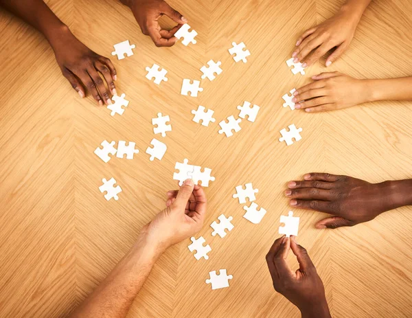 Presto tutto avrà un senso. Colpo ritagliato di un gruppo di uomini d'affari che completano un puzzle insieme su un tavolo. — Foto Stock