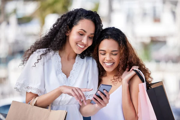 En iyi arkadaşlar seninle en iyi anlaşmaları paylaşır. İki genç kadının şehir geçmişine karşı alışveriş yaparken akıllı telefon kullanması.. — Stok fotoğraf