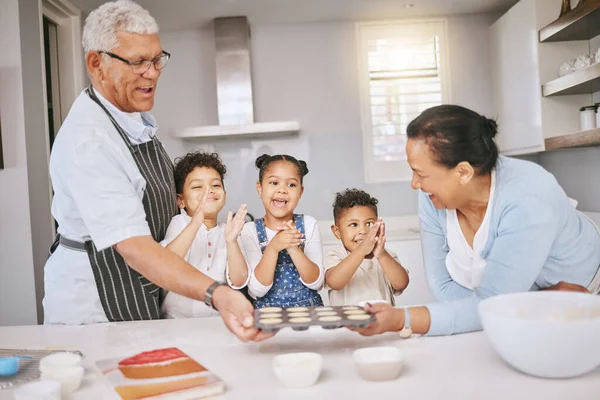 Kunnen we ze nu opeten? Shot van een volwassen paar bakken met hun kleinkinderen thuis. — Stockfoto