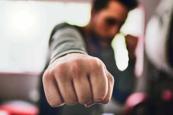 Je čas dát je do práce. Detailní záběr mladého zaostřeného boxera, který během dne háže údery do kamery uvnitř ringu v posilovně. — Stock fotografie