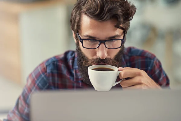 Ele é a combinação especial de artístico, criativo, e tecnicamente inclinado. Tiro de um designer tomando café enquanto trabalhava em seu laptop. — Fotografia de Stock