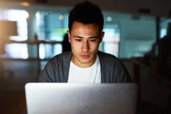 Putting in the hours to meet his deadline. Shot of a handsome young male programmer working late in his office. — ストック写真