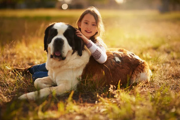 Čím jsou chlupatější, tím lépe se mazlí. Portrét roztomilé holčičky objímající svého psa, zatímco oni hrají venku. — Stock fotografie