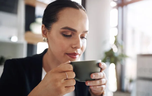 Τα διαλείμματα για καφέ είναι απαραίτητα στις πολυάσχολες μέρες σας. Τραβηγμένο πλάνο μιας ελκυστικής νεαρής επιχειρηματία που πίνει καφέ μέσα στο γραφείο της.. — Φωτογραφία Αρχείου