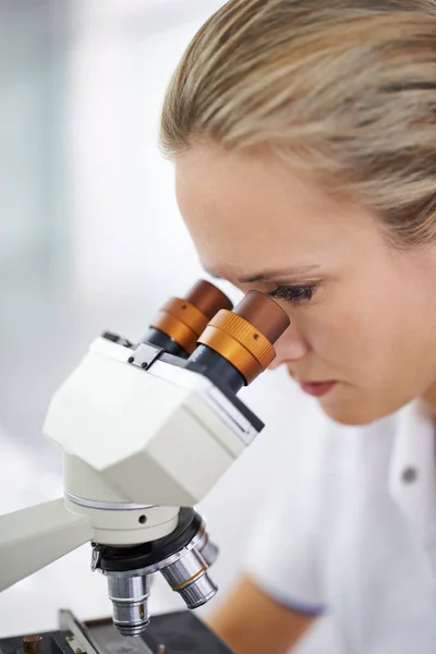 Olhando para o futuro da ciência. Tiro de uma mulher bonita em um laboratório que trabalha com um microscópio. — Fotografia de Stock