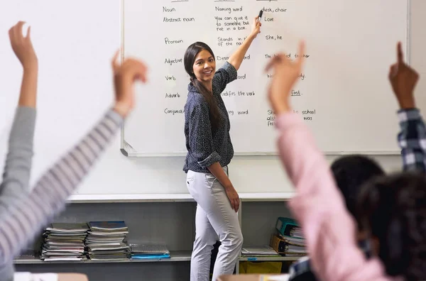 Educar os líderes de amanhã. Tiro de escolares não identificáveis levantando as mãos para responder à pergunta de seus professores na sala de aula. — Fotografia de Stock