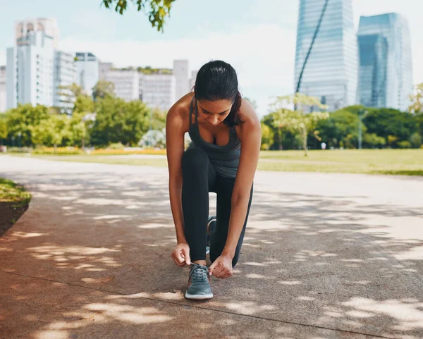 Preparando-se para correr seu caminho para a aptidão. Tiro de comprimento total de uma jovem esportista atraente amarrando seus atacadores ao ar livre na cidade. — Fotografia de Stock