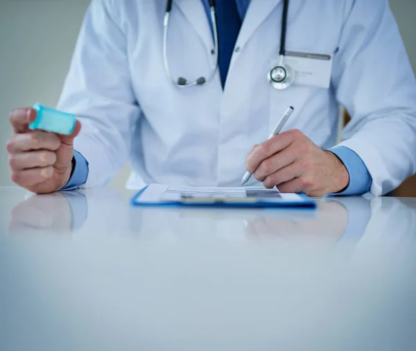 Tenere traccia della tua salute. Primo piano di un medico irriconoscibile che scrive note mentre tiene in mano una bottiglia di farmaco. — Foto Stock