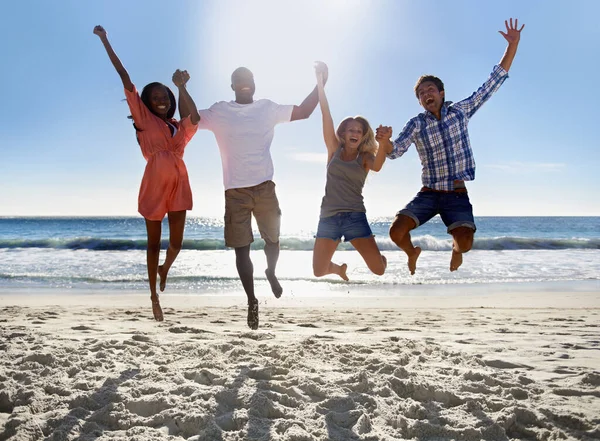 Es verano. Dos parejas jóvenes saltando y divirtiéndose juntas en la playa. — Foto de Stock