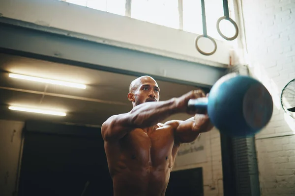 Teljes testerő. Alacsony szögű lövés egy izmos fiatalember gyakorló kettlebell a tornateremben. — Stock Fotó