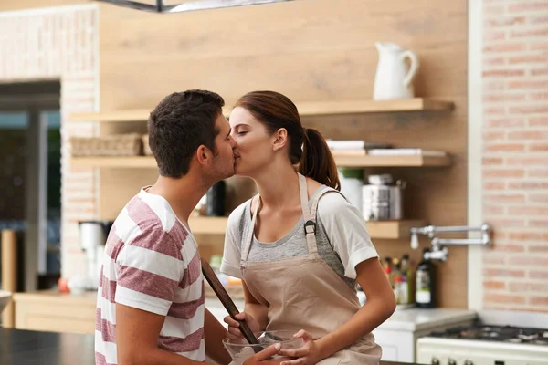 Φιλιά στην κουζίνα. Τραβηγμένο πλάνο ενός νεαρού ζευγαριού να μοιράζεται ένα φιλί στην κουζίνα. — Φωτογραφία Αρχείου
