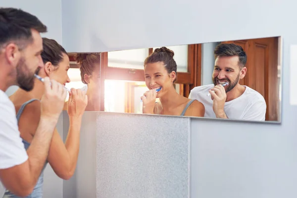 Their daily early morning routine. Shot of a young couple brushing their teeth together at home. — Stock Photo, Image