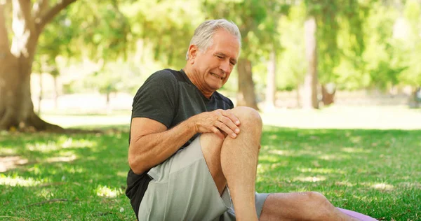 His joints are not as young as they used to be. Cropped shot of a senior man suffering a knee injury while out for a workout. — Stock Photo, Image