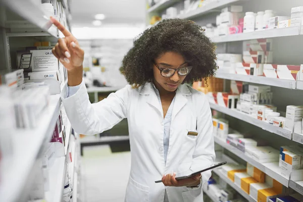 Це в потрібному місці. Знімок веселого молодого жіночого фармацевта, який перевіряє запаси на полицях аптеки . — стокове фото