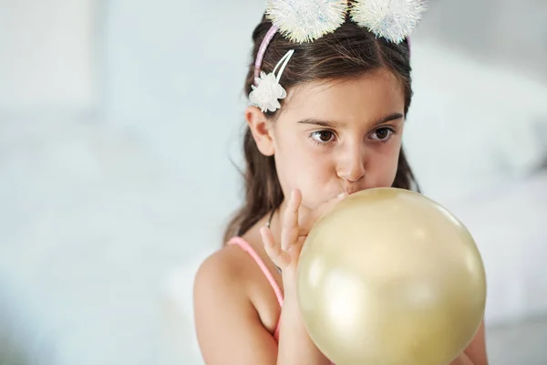 Chcę zobaczyć, jak duże to będzie. Strzał uroczej dziewczynki wysadzającej balon na przyjęciu urodzinowym. — Zdjęcie stockowe