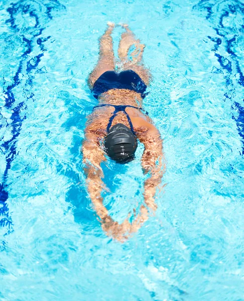 Скользящие оставшиеся несколько метров. Высокоугол обзора женщины-пловца, скользящей по бассейну. — стоковое фото