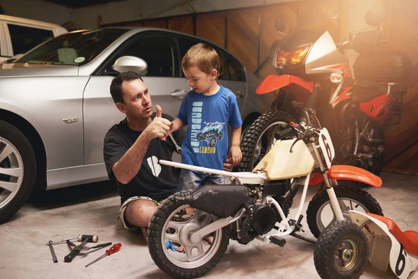 Ser um modelo para o seu filho. Tiro de um pai e filho fixando uma bicicleta em uma garagem. — Fotografia de Stock