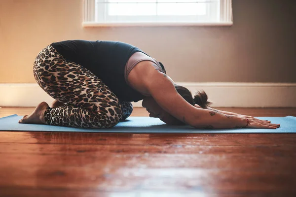 Você deve sentir-se à vontade com cada alongamento. Tiro de uma jovem praticando ioga em casa. — Fotografia de Stock