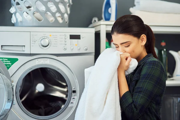 Vůně čerstvého prádla. Vystřižený záběr atraktivní mladé ženy čichající čerstvě vypraný ručník při praní prádla doma. — Stock fotografie