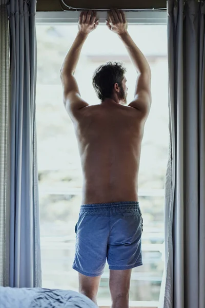 Adoro a minha vista. Rearview tiro de um homem irreconhecível olhando pela janela em casa. — Fotografia de Stock