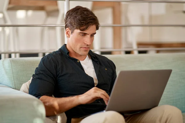 Z internetem zawsze jesteś we właściwym miejscu i czasie. Przycięte ujęcie mężczyzny korzystającego z laptopa podczas relaksu na kanapie w domu. — Zdjęcie stockowe
