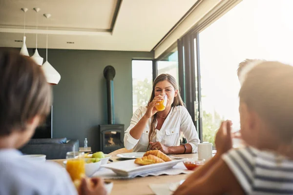 A mãe adora ouvir todas as suas histórias ao pequeno-almoço. Tiro de uma mãe tomando café da manhã com seus filhos em casa. — Fotografia de Stock
