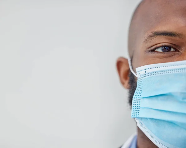 Hij is altijd gemaskeerd. Close-up shot van een jonge arts met een masker op het werk. — Stockfoto