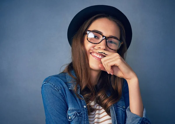 Ive got a finger full of fun. Shot of a comical young woman posing with a mustache drawn on her finger in studio. —  Fotos de Stock