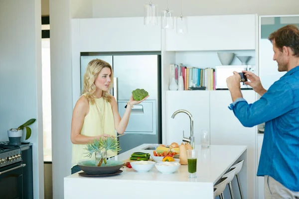 Der Star der Show ist Brokkoli. Aufnahme eines Ehemannes, der Schnappschüsse seiner Frau bei der Zubereitung einer gesunden Mahlzeit zu Hause macht. — Stockfoto