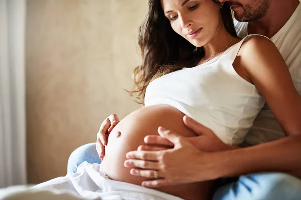 Ligação com o bebé. Tiro de um marido e mulher grávida sentados juntos em um quarto. — Fotografia de Stock