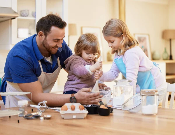 Η κουζίνα είναι η καρδιά του σπιτιού. Πυροβολισμός ενός νεαρού πατέρα να ψήνεται μαζί ενώ ένα μικρό κορίτσι ανακατεύει ένα μπολ με κέικ.. — Φωτογραφία Αρχείου