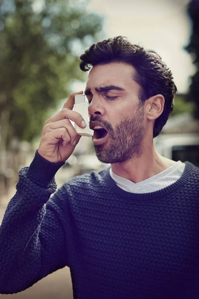 Getting his symptoms under control. Cropped shot of a young man using his asthma pump outside. — Stock Photo, Image
