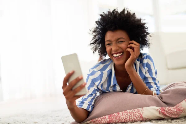 Dias de lazer em casa. Tiro de uma jovem mulher enviando mensagens de texto em seu celular em casa. — Fotografia de Stock