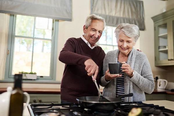 Déjame a mí toda la cocina. Toma de una cariñosa pareja de ancianos cocinando juntos en su cocina en casa. — Foto de Stock
