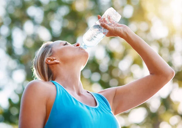 Bleiben Sie während Ihres Trainings immer hydratisiert. Flachbild einer reifen Frau, die im Freien Wasser aus einer Flasche trinkt. — Stockfoto