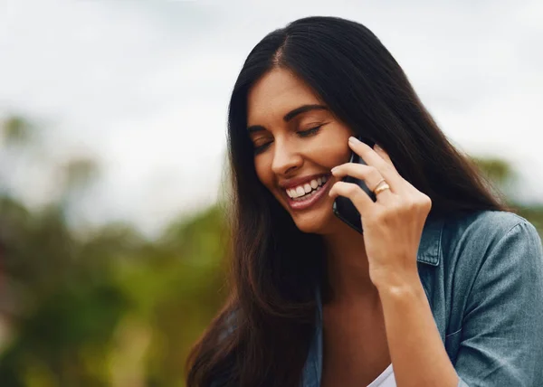 Ik ben zo blij dat je belde. Foto van een aantrekkelijke jonge vrouw met behulp van een mobiele telefoon in een park. — Stockfoto