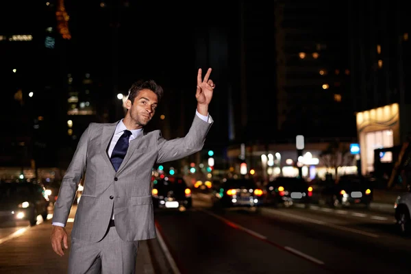 Taxi. Un hombre de negocios guapo llamando a un taxi mientras está de pie en una calle de la ciudad ocupada por la noche. — Foto de Stock