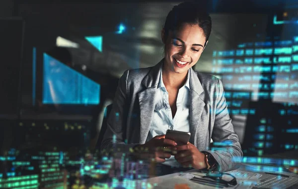 Networking through the night. Shot of a young businesswoman working late at night in a modern office superimposed over a cityscape. — Photo