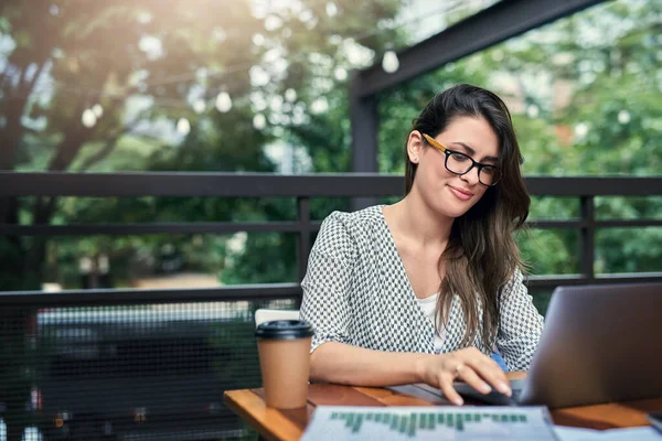 Productief zijn buiten het kantoor. Gehakt schot van een aantrekkelijke jonge zakenvrouw werken op haar laptop terwijl zitten buiten in een cafe. — Stockfoto