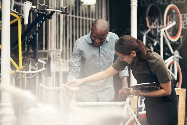 Do you think shell like this. Shot of an attractive young woman standing outside her bicycle shop and assisting a customer. — 스톡 사진