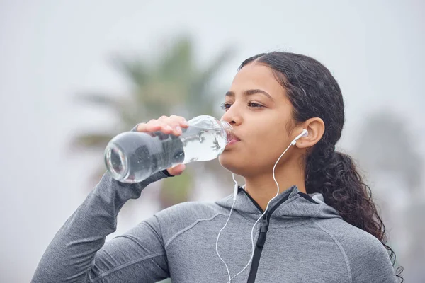 Dont forget to keep yourself hydrated. Shot of a young woman drinking water while exercising in nature. — 스톡 사진