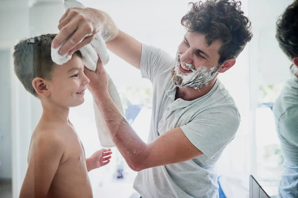 Güne temiz ve taze başlıyoruz. Bir babanın evdeki banyoda tıraş olurken oğlunun yüzünü silmesi.. — Stok fotoğraf