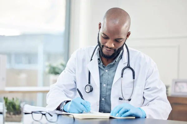 Дослідження ніколи не закінчується, навіть коли ви кваліфіковані. Знімок красивого молодого лікаря, який сидить один у своїй клініці і робить нотатки . — стокове фото