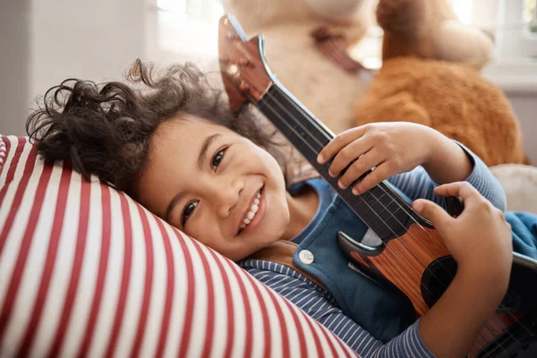 Een glimlach die rozen doet bloeien. Portret van een schattige jonge jongen die thuis met een gitaar speelt in zijn slaapkamer. — Stockfoto