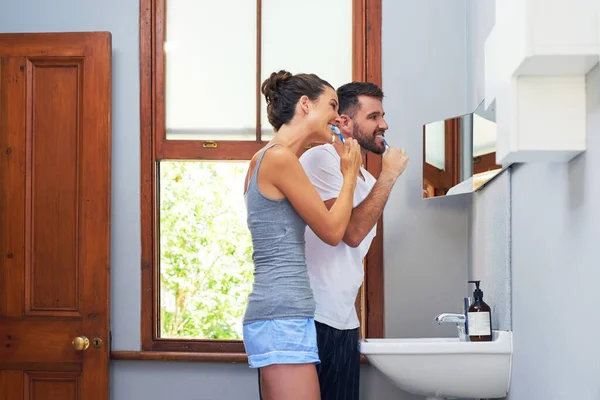 Cuidando de seus brancos perolados juntos. Tiro de um jovem casal escovando os dentes juntos em casa. — Fotografia de Stock