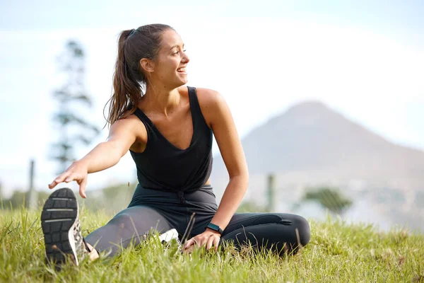 Certifique-se de começar sempre com um bom alongamento. Tiro de uma jovem esportiva esticando as pernas enquanto se exercita ao ar livre. — Fotografia de Stock