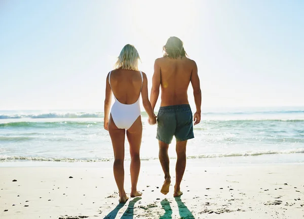 Há algo de romântico num passeio pela praia. Foto retrovisor de um jovem casal desfrutando de algum tempo de qualidade juntos na praia. — Fotografia de Stock